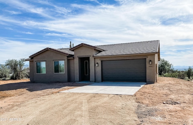 view of front facade with a tile roof, stucco siding, concrete driveway, and a garage