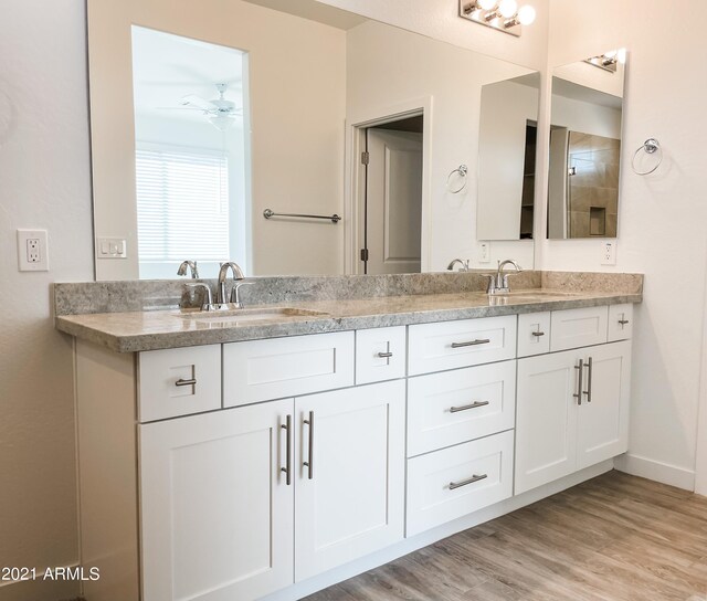 full bath with a sink, wood finished floors, double vanity, and ceiling fan