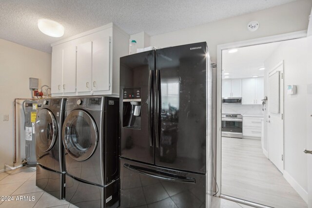 laundry room featuring a textured ceiling, light hardwood / wood-style flooring, and washer and dryer