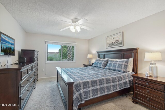 bedroom with ceiling fan, light carpet, and a textured ceiling