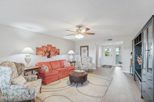 living room with light wood-type flooring, a textured ceiling, and ceiling fan