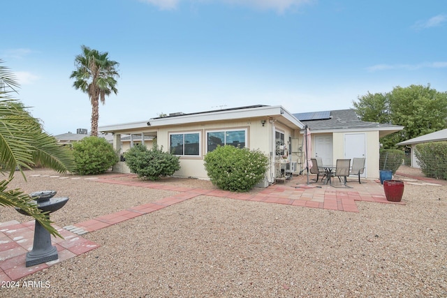 rear view of property featuring solar panels and a patio