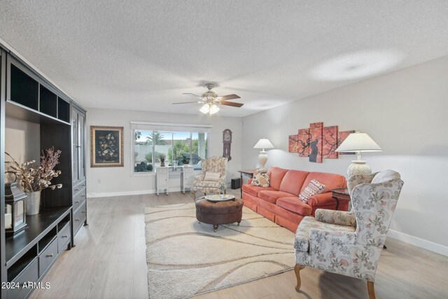 living room with light hardwood / wood-style floors, a textured ceiling, and ceiling fan