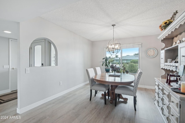 dining space featuring a textured ceiling, a chandelier, and light wood-type flooring