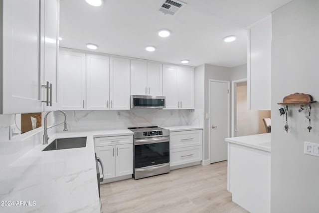 kitchen with backsplash, sink, appliances with stainless steel finishes, light hardwood / wood-style floors, and white cabinets