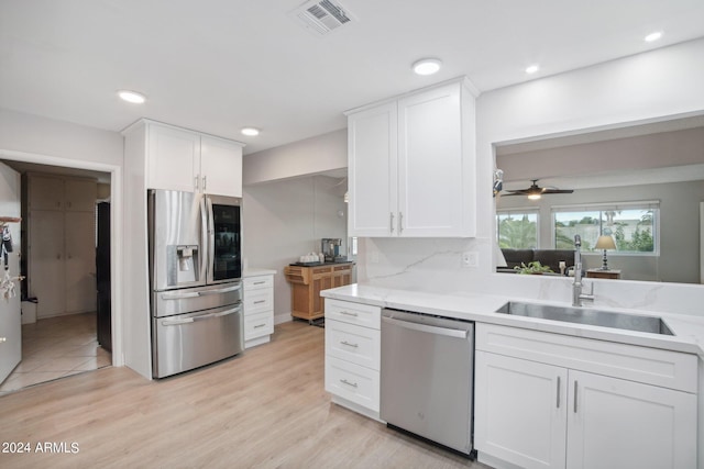 kitchen with ceiling fan, light wood-type flooring, decorative backsplash, sink, and stainless steel appliances