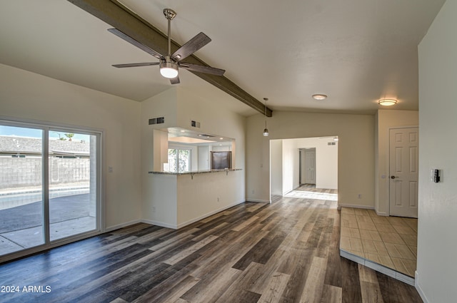 unfurnished living room featuring ceiling fan, a healthy amount of sunlight, dark hardwood / wood-style flooring, and vaulted ceiling with beams