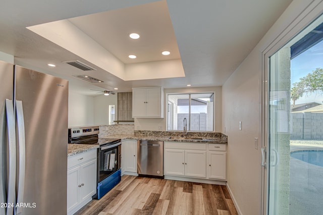 kitchen with light stone countertops, appliances with stainless steel finishes, sink, and white cabinets