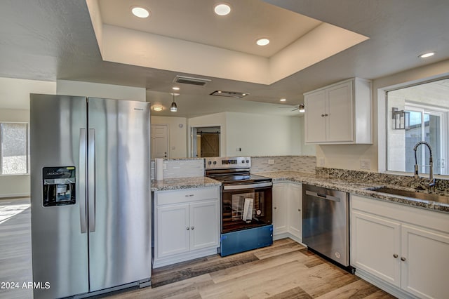 kitchen with sink, white cabinetry, appliances with stainless steel finishes, light stone countertops, and light hardwood / wood-style floors