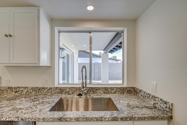 kitchen with white cabinetry, sink, and light stone counters