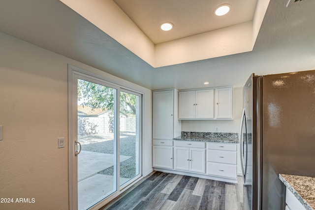 kitchen featuring white cabinetry, black refrigerator, dark wood-type flooring, and light stone counters