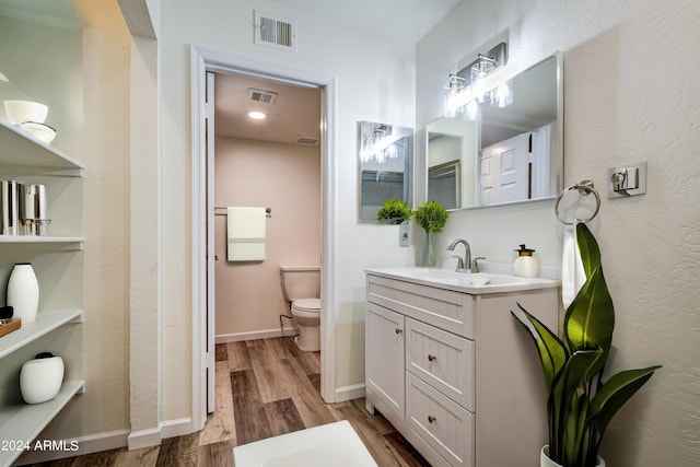 bathroom featuring vanity, wood-type flooring, and toilet