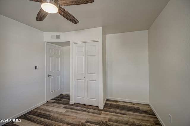 unfurnished bedroom with ceiling fan, dark hardwood / wood-style floors, and a closet