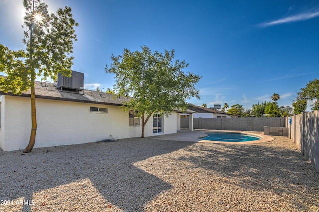 back of property featuring a fenced in pool, central AC, and a patio