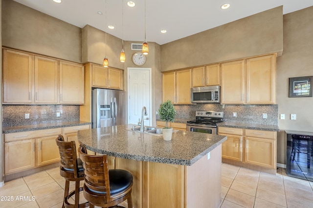 kitchen featuring light brown cabinetry, stainless steel appliances, and dark stone counters