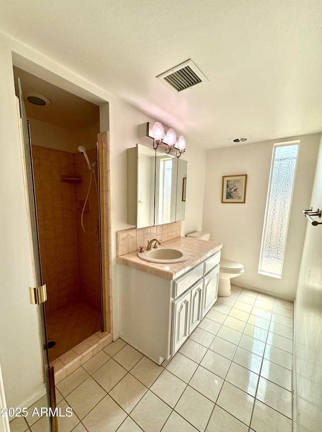 bathroom featuring a shower stall, vanity, visible vents, toilet, and tile patterned floors