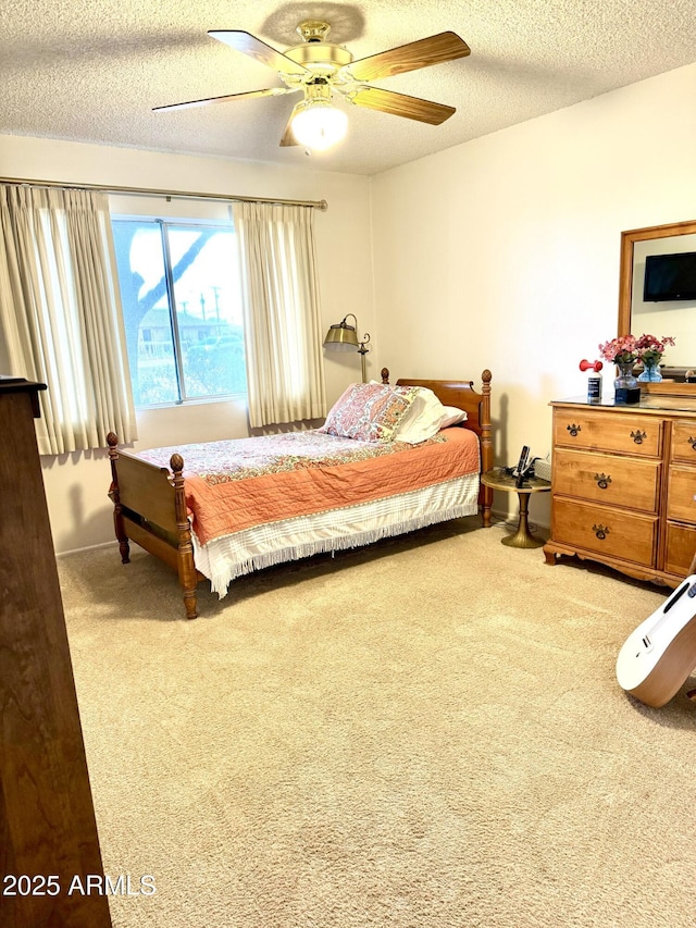 carpeted bedroom featuring a ceiling fan and a textured ceiling