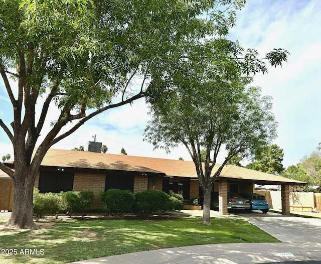 ranch-style home featuring a carport, a front lawn, brick siding, and concrete driveway