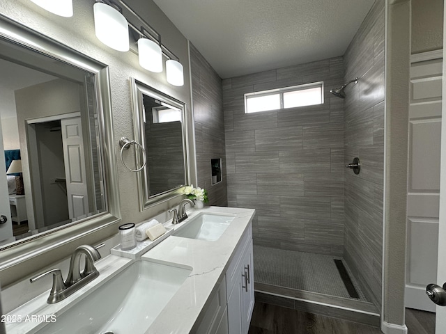 15075 W Amelia Dr, Goodyear, AZ 85395 - bathroom with a tile shower, double vanity, and wood finished floors