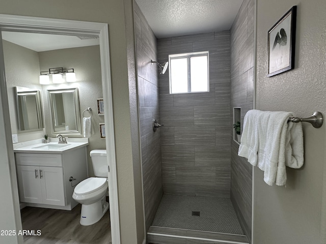 15075 W Amelia Dr, Goodyear, AZ 85395 - bathroom with tiled shower, vanity, a textured wall, and wood finished floors