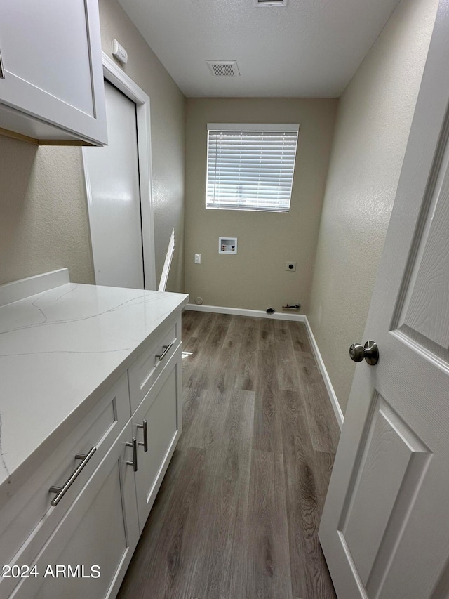 washroom featuring hookup for an electric dryer, hookup for a washing machine, cabinets, and light wood-type flooring