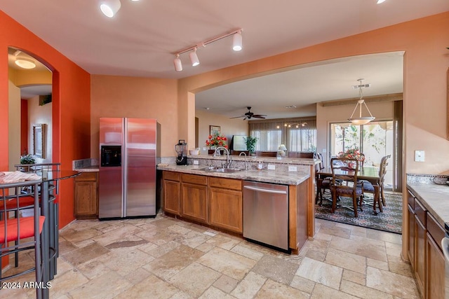 kitchen with kitchen peninsula, stainless steel appliances, ceiling fan, sink, and hanging light fixtures