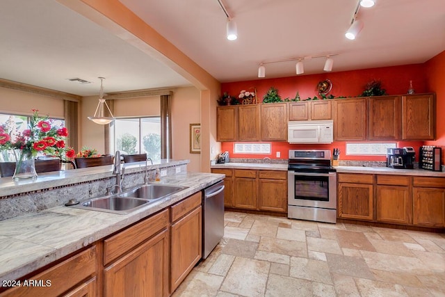 kitchen featuring sink, track lighting, decorative light fixtures, and appliances with stainless steel finishes