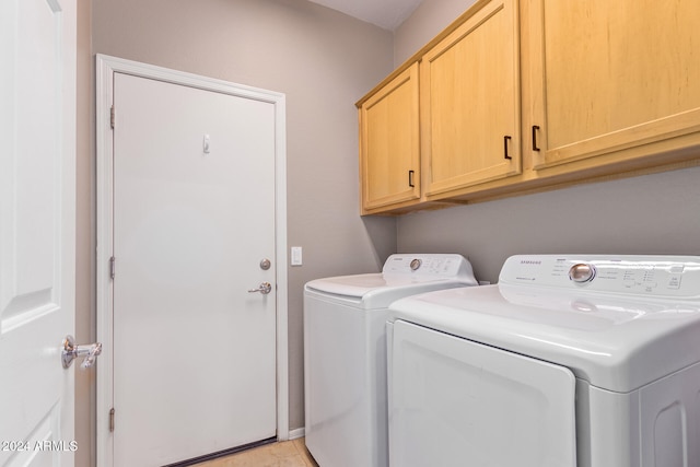 clothes washing area featuring washing machine and dryer and cabinets