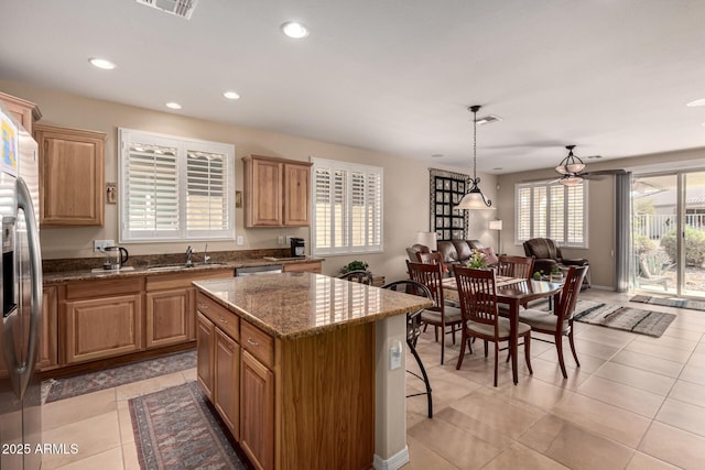 kitchen featuring stone counters, decorative light fixtures, a center island, light tile patterned floors, and stainless steel fridge with ice dispenser