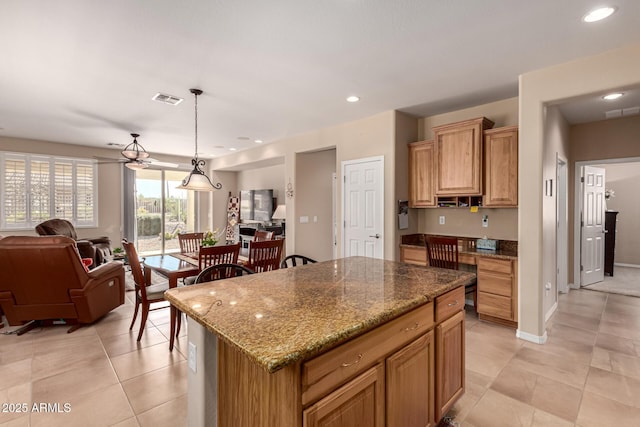 kitchen featuring stone countertops, decorative light fixtures, a kitchen island, and light tile patterned floors