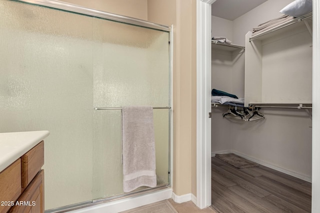 bathroom featuring wood-type flooring, vanity, and a shower with shower door