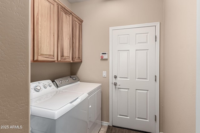 clothes washing area featuring cabinets and washing machine and clothes dryer