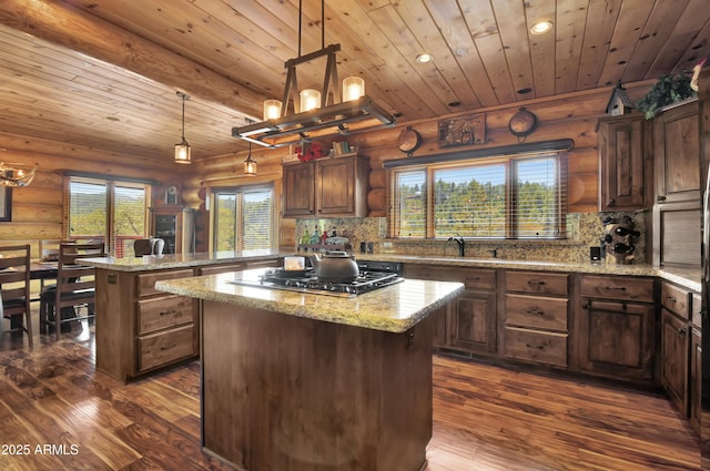 kitchen featuring a center island, decorative backsplash, stainless steel gas cooktop, and decorative light fixtures