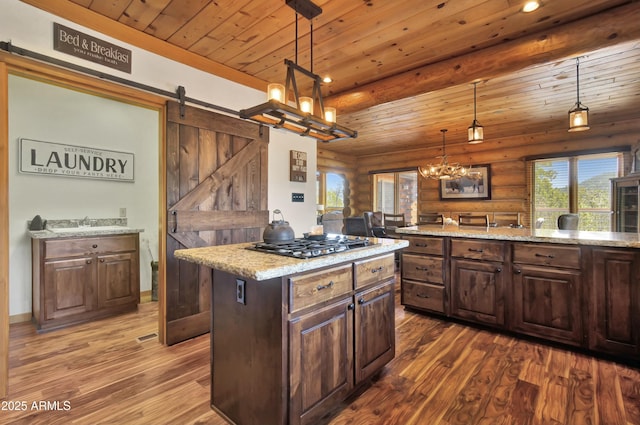 kitchen featuring a barn door, dark brown cabinetry, decorative light fixtures, and a center island