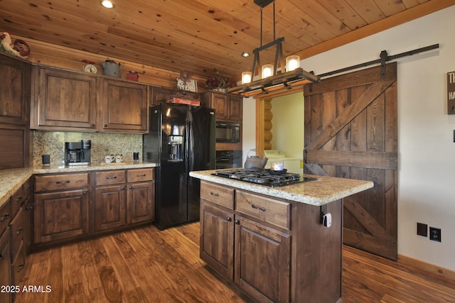 kitchen with decorative light fixtures, wooden ceiling, a kitchen island, a barn door, and black appliances