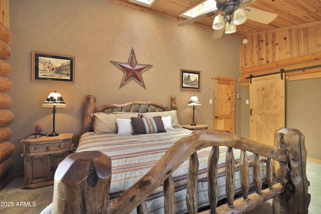 carpeted bedroom featuring wood ceiling, a skylight, and a barn door