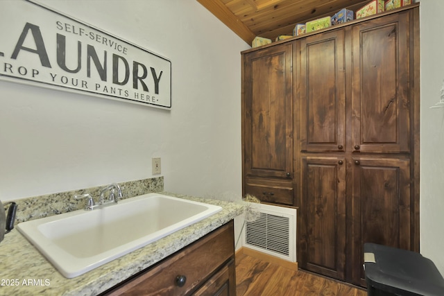 clothes washing area with dark hardwood / wood-style flooring, sink, and wood ceiling