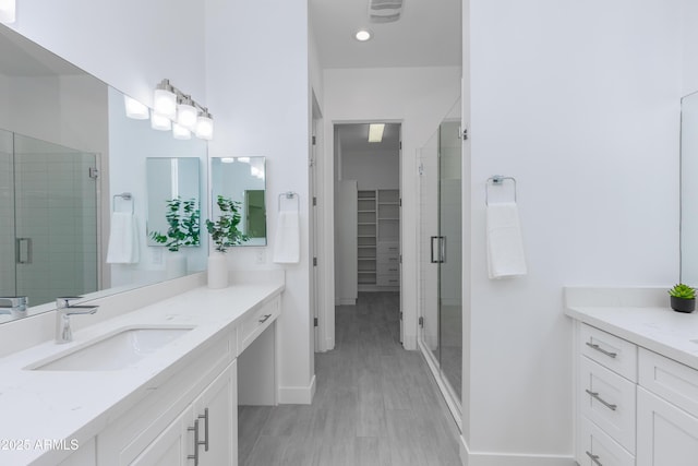 bathroom with a stall shower, two vanities, and a sink