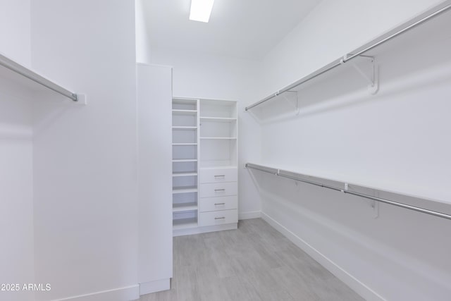 walk in closet with light wood finished floors