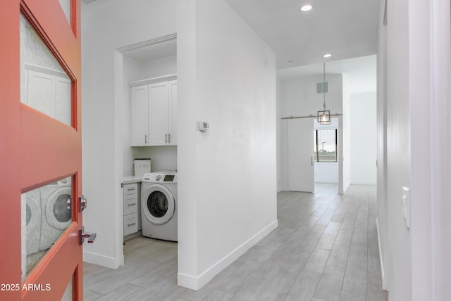 clothes washing area featuring a barn door, cabinet space, washer / dryer, and baseboards