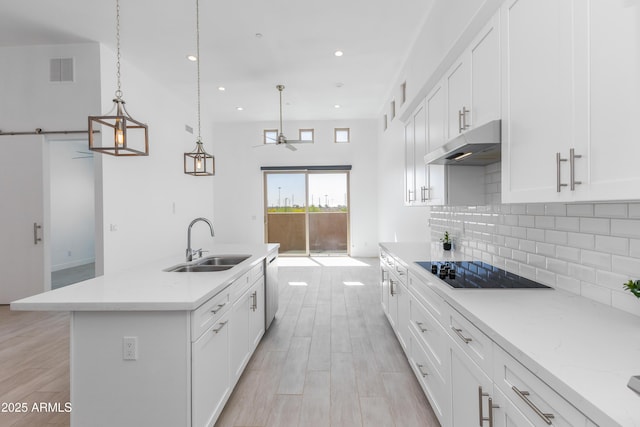 kitchen with visible vents, a sink, black electric stovetop, under cabinet range hood, and backsplash