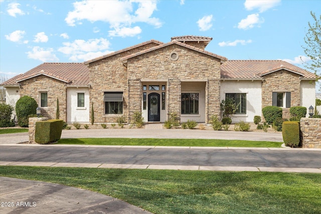 mediterranean / spanish home featuring stone siding, stucco siding, and a tiled roof