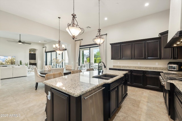 kitchen with light stone counters, ceiling fan with notable chandelier, stainless steel appliances, and a sink