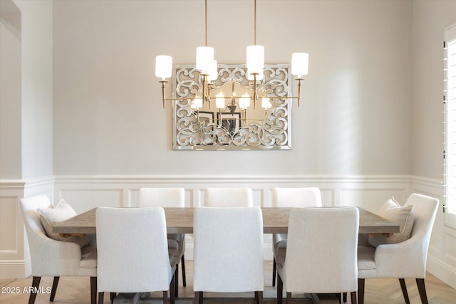 dining space with a chandelier, wainscoting, and a decorative wall