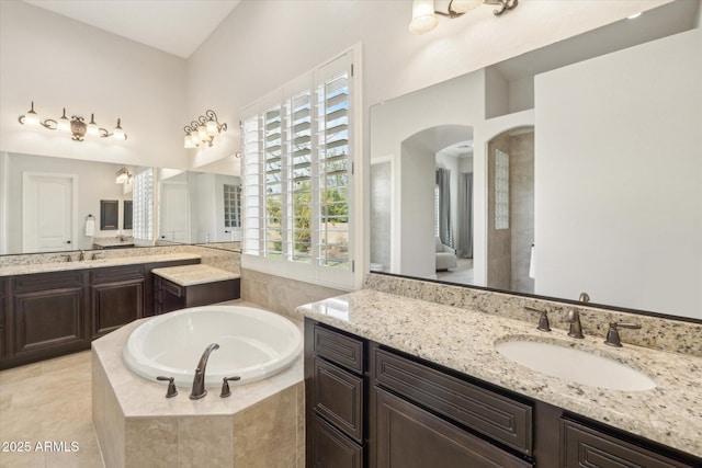 bathroom with a sink, two vanities, and a bath