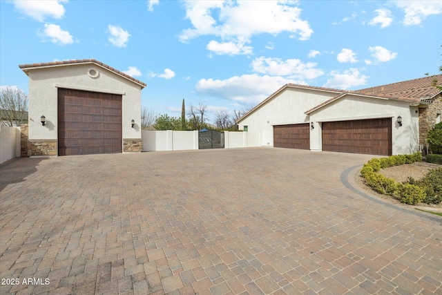 garage featuring fence, decorative driveway, and a gate