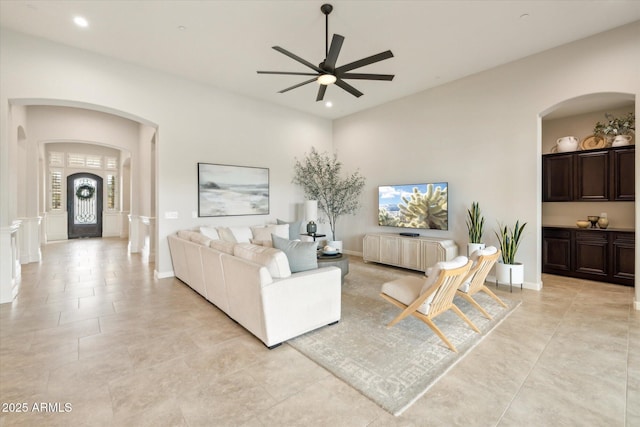 living area with arched walkways, light tile patterned floors, recessed lighting, and a ceiling fan