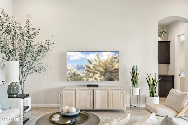 living area with baseboards and arched walkways