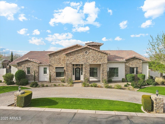 mediterranean / spanish-style home with stone siding, stucco siding, and a tiled roof