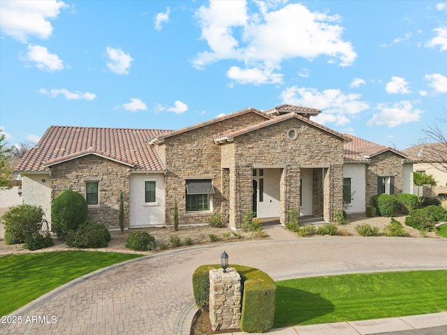 mediterranean / spanish-style house featuring a tile roof, stone siding, a front yard, and stucco siding